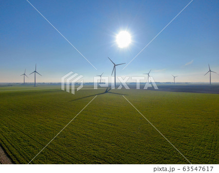 Aerial view of wind turbines on agricultural fields during blue winter day Aerial view of wind turbines on agricultural fields during blue winter day 63547617