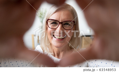 Happy older woman in eyeglasses making heart symbol. Happy older woman in eyeglasses making heart symbol. 63548953