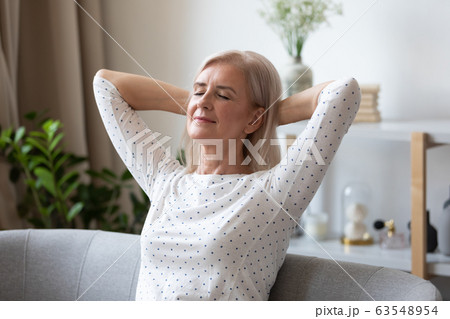 Peaceful middle aged pleasant woman daydreaming on comfortable sofa. 63548954