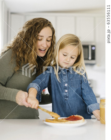 Woman making peanut butter and jelly sandwich with her daughter 63556111