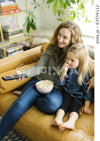 Mother and daughter with bowl of popcorn watching movie 63556112