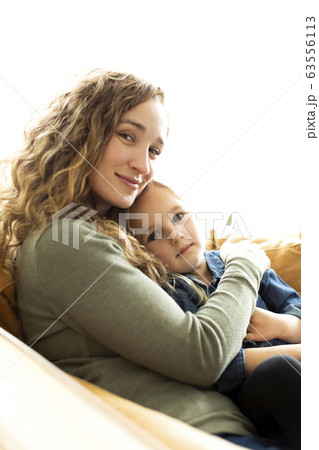 Mother and daughter sitting on sofa 63556113