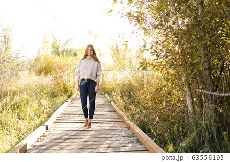 Smiling woman standing on forest boardwalk Smiling woman standing on forest boardwalk 63556195