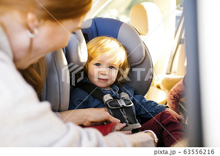 Boy having his seat belt buckled by his mother 63556216
