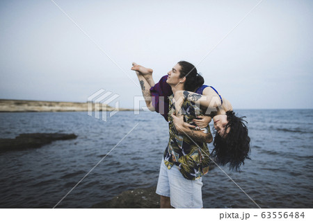 Young man carrying woman on beach 63556484