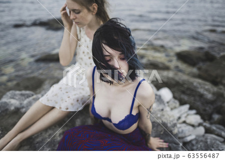 Young women sitting together on beach Young women sitting together on beach 63556487