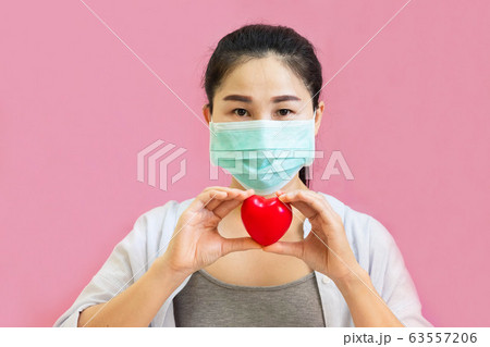 Young asian woman wore protective masks against virus and air pollution,holding red heart Young asian woman wore protective masks against virus and air pollution,holding red heart 63557206