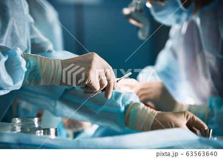 Doctor's hand with latex gloves taking stainless tweezers to help people with patience, on a white gray background. Modern medecine, life saving 63563640