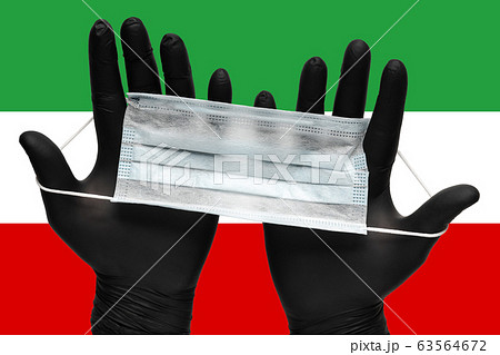 Doctor holds face mask in black medical gloves on background colors flag of Islamic Republic of Iran. Pandemic insurance coronavirus 63564672