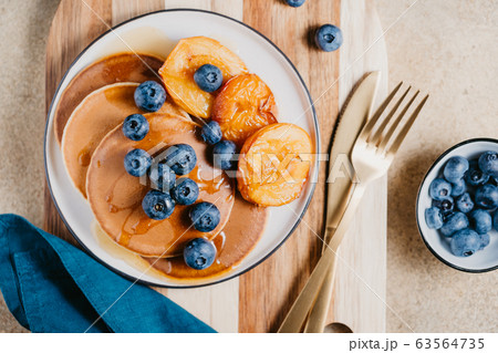 Top view of pancakes with grilled peaches, fresh blueberry and maple syrup. Top view of pancakes with grilled peaches, fresh blueberry and maple syrup. 63564735