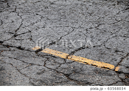 Cracked asphalt road with yellow dividing line 63568034