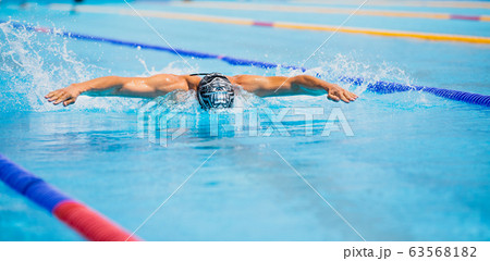 Athletic man swimming in butterfly style in the swimming pool with clear blue water. Athletic man swimming in butterfly style in the swimming pool with clear blue water. 63568182
