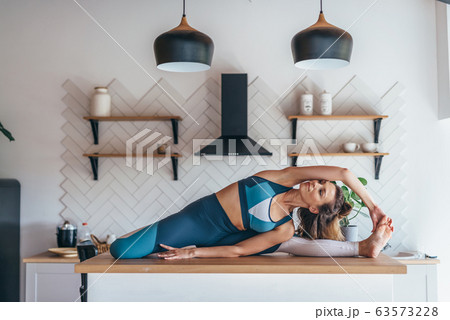 Women stretching at home doing seated side bend. Women stretching at home doing seated side bend. 63573228