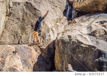 A man jumping from a cliff into a river 63573527