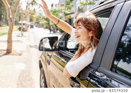 Woman i car waving to friend Woman i car waving to friend 63574350