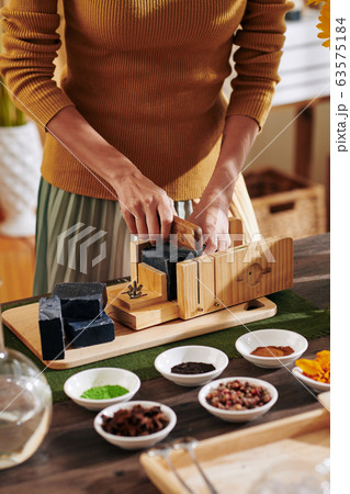 Woman cutting loaf of black soap 63575184