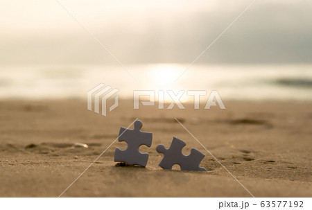 Jigsaw on the beach sand matching puzzle pieces together 63577192