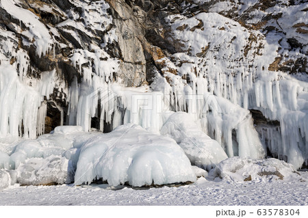 Baikal Lake in the winter cold day. Beautiful icy rocks with big ice crust.long icicles on the icy coastal cliffs of Olkhon Island 63578304