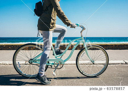 Unrecognizable young woman rides on bicycle 63578857