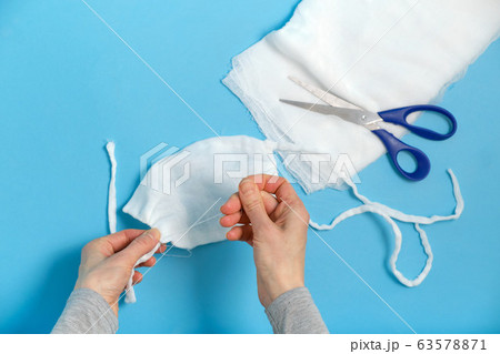 A woman sews a mask during a pandemic quarantine. The concept of deficiency. A woman sews a mask during a pandemic quarantine. The concept of deficiency. 63578871