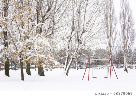 Snowy park with swings and trees 63579069