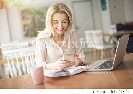 Young woman in cafe sitting browsing smartphone smiling joyful Young woman in cafe sitting browsing smartphone smiling joyful 63579375