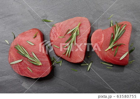 Raw tuna steak with rosemary on black stone 63580755