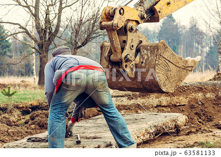 The worker unlocks the chains from the concrete 63581133