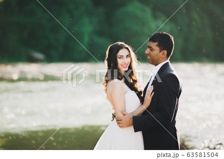 Wedding couple, groom and bride hugging, outdoor near river 63581504