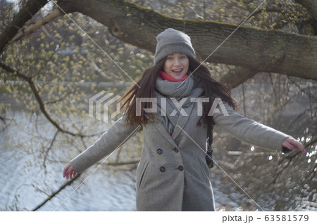 Portrait of cheerful young woman at the background of water in park or forest. Positive Caucasian girl having fun outdoors on sunny autumn day. Leisure, happiness, lifestyle. Portrait of cheerful young woman at the background of water in park or forest. Positive Caucasian girl having fun outdoors on sunny autumn day. Leisure, happiness, lifestyle. 63581579