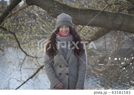 Portrait of happy young Caucasian woman in warm clothes smiling at camera. Cheerful beautiful brunette girl posing outdoors on sunny autumn day. Joy, leisure, lifestyle. Portrait of happy young Caucasian woman in warm clothes smiling at camera. Cheerful beautiful brunette girl posing outdoors on sunny autumn day. Joy, leisure, lifestyle. 63581583
