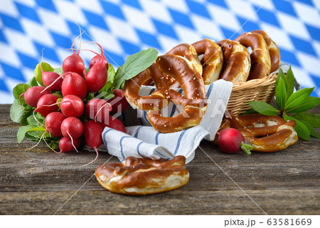 Radishes and fresh Bavarian pretzels in a breadbasket on a wooden table 63581669