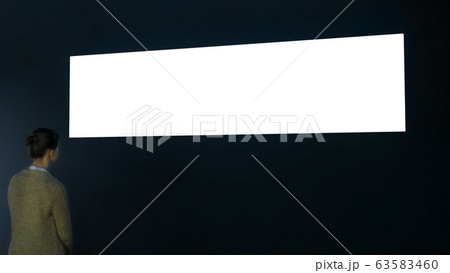 Woman looking at large blank white screen - isolated concept Woman looking at large blank white screen - isolated concept 63583460