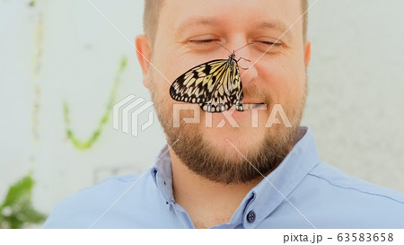 large brown butterfly sits on the nose of a male face, close-up. Copy space large brown butterfly sits on the nose of a male face, close-up. Copy space 63583658