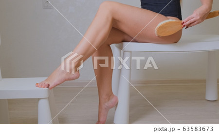 Pretty redhead girl massages the skin of her legs with a brush for a dry massage. Beautiful redhead Pretty redhead girl massages the skin of her legs with a brush for a dry massage. Beautiful redhead 63583673