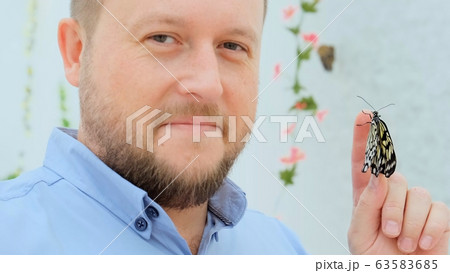 male holds a butterfly on his hand and examines it and admires the beauty of the insect, close-up male holds a butterfly on his hand and examines it and admires the beauty of the insect, close-up 63583685