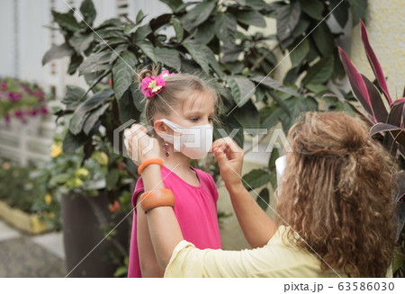 Woman and daughter wearing facial disposable mask. Woman and daughter wearing facial disposable mask. 63586030