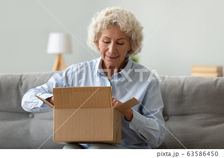 Happy elderly woman open parcel shopping online Happy elderly woman open parcel shopping online 63586450