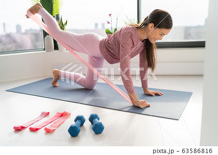 Resistance band fitness at home Asian woman doing leg workout donkey kick floor exercises with strap elastic. Glute muscle activation with kickback for thighs cellulite 63586816