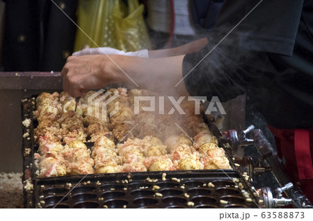 Vendor making takoyaki on a takoyaki pan in Osaka, 63588873