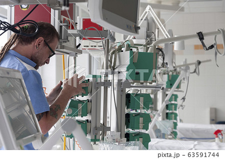 Male nurse checks the function of syringe infusion pump 63591744