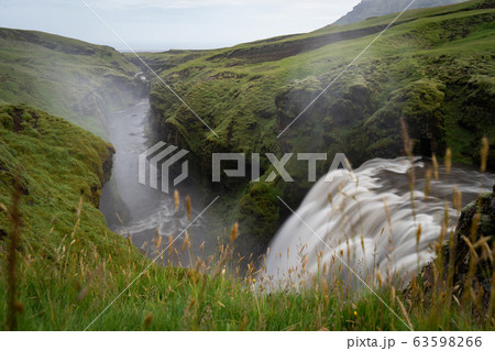 Beautiful smooth waterfall in Iceland surrounded by green hills 63598266