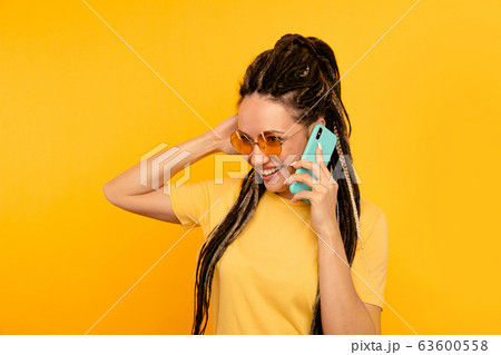 Exited woman talking phone in the yellow studio. 63600558