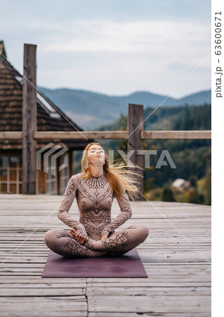 A woman sitting in lotus position at the morning on a fresh air. 63600671