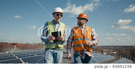Engineer and technician discussing between solar panels Engineer and technician discussing between solar panels 63601238