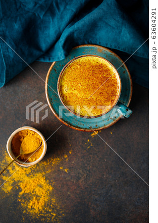 Top down view of turmeric latte cup on a textured dark background. Top down view of turmeric latte cup on a textured dark background. 63604291
