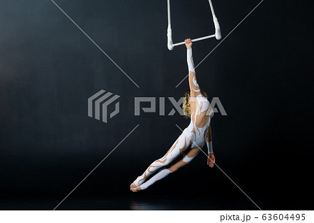 A young girl performs the acrobatic elements in the air trapeze