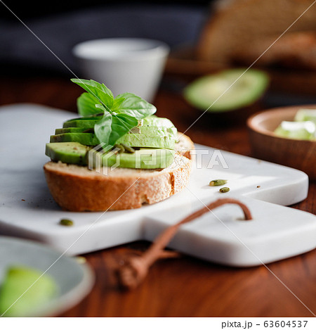 Avocado toast with cherry tomatoes and pepitas on a cutting board. Home cooking, healthy eating concept 63604537