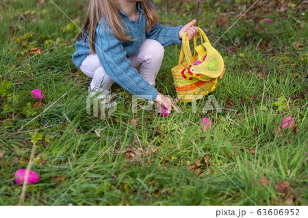 Girl collects the eggs in a basket for Easter 63606952
