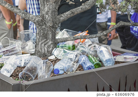 Garbage from cans and plastic and paper in a pot with a tree 63606976